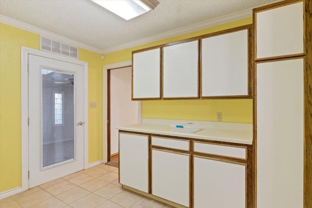 kitchen featuring white cabinetry, ornamental molding, a textured ceiling, and light tile patterned floors