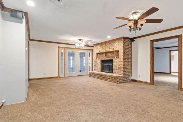 unfurnished living room with light colored carpet, ceiling fan, crown molding, a brick fireplace, and a textured ceiling