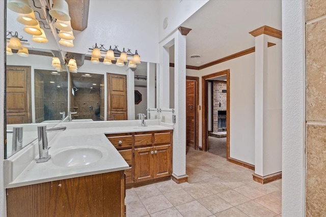 bathroom with a fireplace, a chandelier, tile patterned flooring, vanity, and crown molding