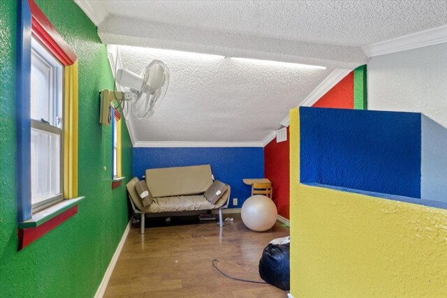 interior space featuring crown molding, wood-type flooring, and a textured ceiling