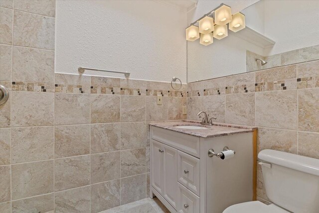 bathroom with vanity, tile walls, and toilet