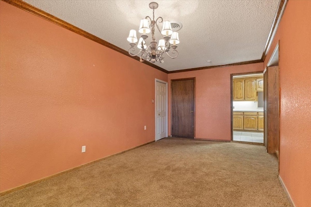 unfurnished room with an inviting chandelier, ornamental molding, light colored carpet, and a textured ceiling