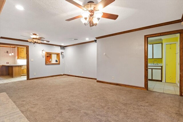 carpeted spare room with sink, ornamental molding, a textured ceiling, and ceiling fan