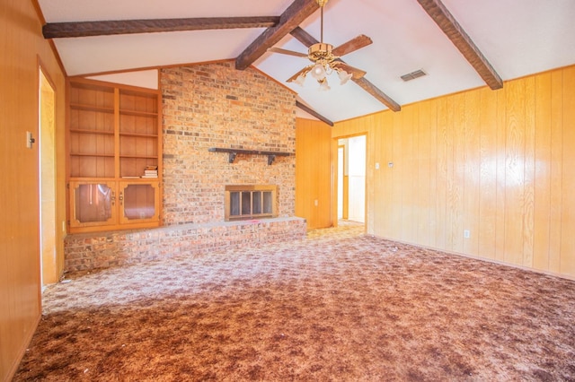 unfurnished living room with wooden walls, a fireplace, carpet, and vaulted ceiling with beams