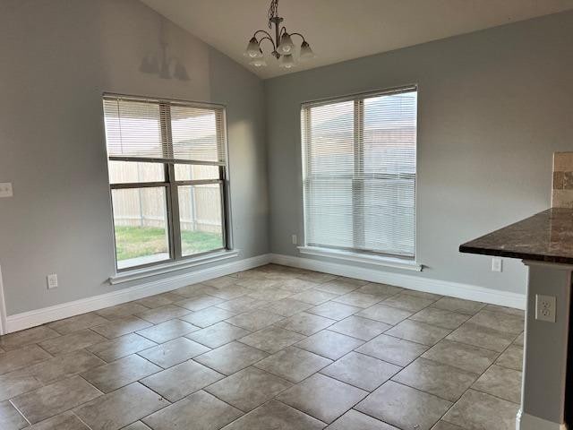 unfurnished dining area featuring an inviting chandelier, vaulted ceiling, and light tile patterned flooring