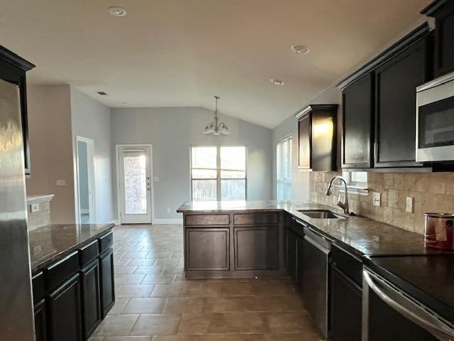 kitchen with vaulted ceiling, pendant lighting, sink, decorative backsplash, and stainless steel appliances