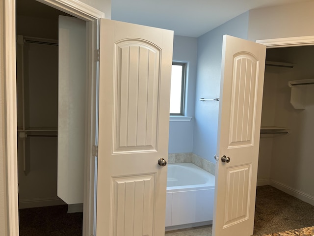 bathroom with baseboards and a bath