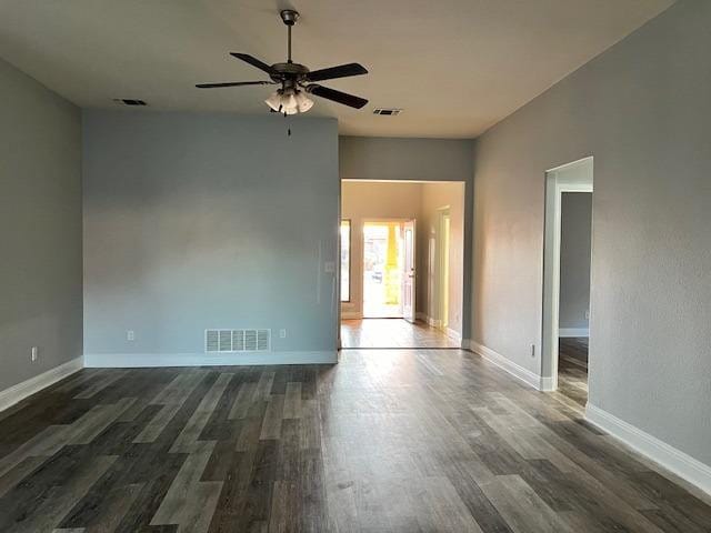 unfurnished room with a ceiling fan, baseboards, visible vents, and dark wood-style flooring