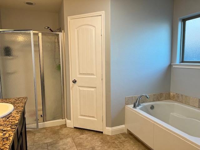 bathroom with a stall shower, vanity, baseboards, and a bath