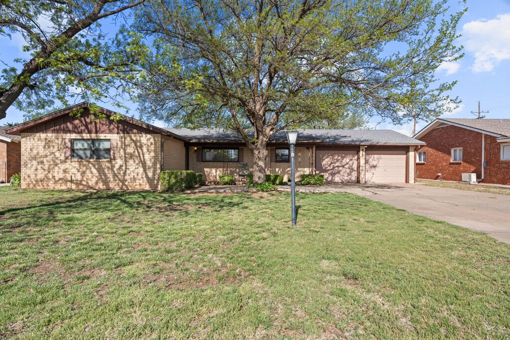 817 Holliday St, Plainview, TX 79072 - ranch-style house with concrete driveway, brick siding, a front yard, and a garage