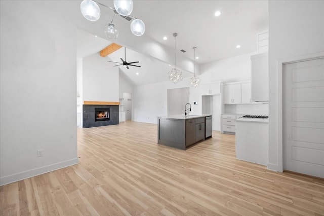 kitchen featuring hanging light fixtures, high vaulted ceiling, an island with sink, white cabinets, and beamed ceiling