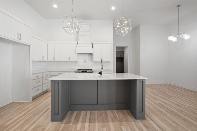 kitchen featuring pendant lighting, light hardwood / wood-style flooring, decorative backsplash, and white cabinets