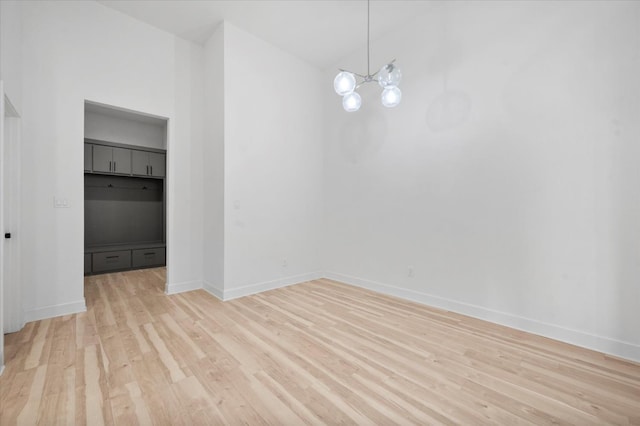 spare room with light wood-type flooring and a notable chandelier