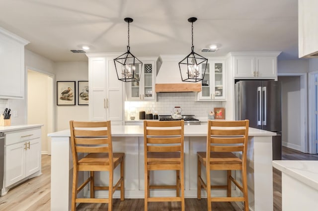 kitchen with premium range hood, white cabinets, a kitchen bar, and decorative light fixtures