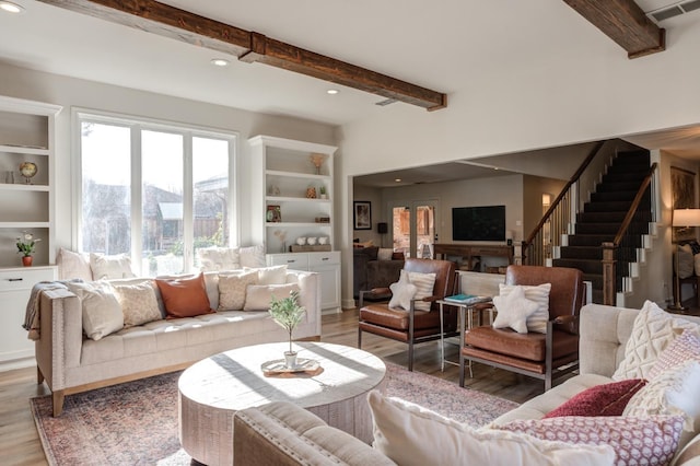 living room featuring built in shelves, beam ceiling, a mountain view, and hardwood / wood-style floors