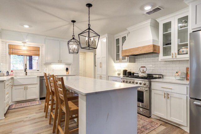 kitchen featuring sink, appliances with stainless steel finishes, white cabinets, and premium range hood