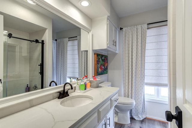 bathroom featuring vanity, wood-type flooring, walk in shower, and toilet