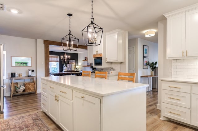 kitchen featuring white cabinetry, a center island, hanging light fixtures, and light wood-type flooring