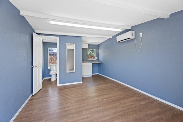 interior space featuring beamed ceiling, dark hardwood / wood-style flooring, and an AC wall unit