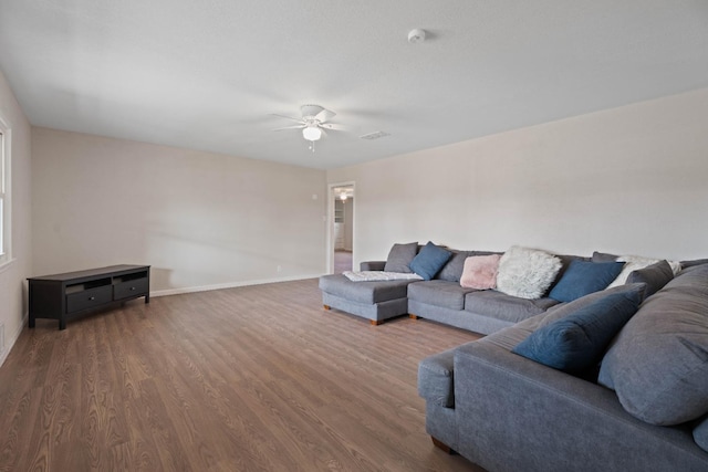 living room featuring dark wood-type flooring and ceiling fan