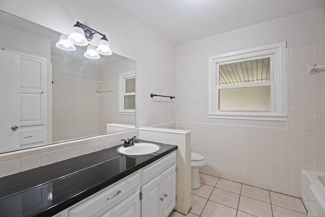 bathroom with tile walls, a chandelier, vanity, toilet, and tile patterned floors