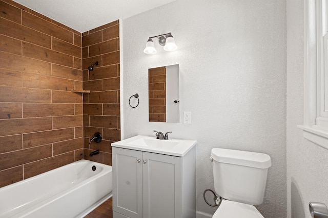 full bathroom featuring tiled shower / bath, vanity, and toilet