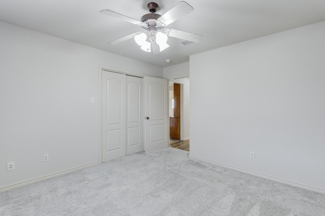 unfurnished bedroom with light carpet, ceiling fan, and a closet