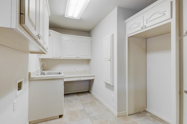 laundry room with washer hookup, sink, cabinets, and a textured ceiling