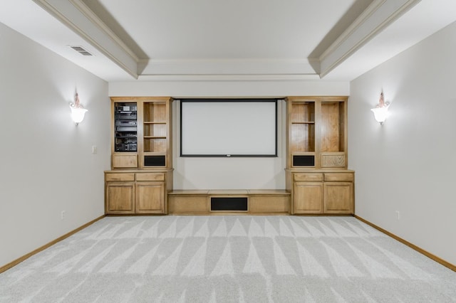 home theater featuring light carpet, a tray ceiling, and ornamental molding