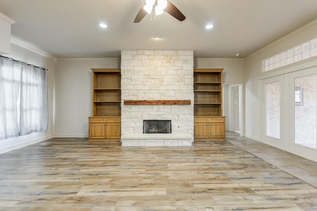 unfurnished living room with crown molding, light wood-type flooring, ceiling fan, and a fireplace