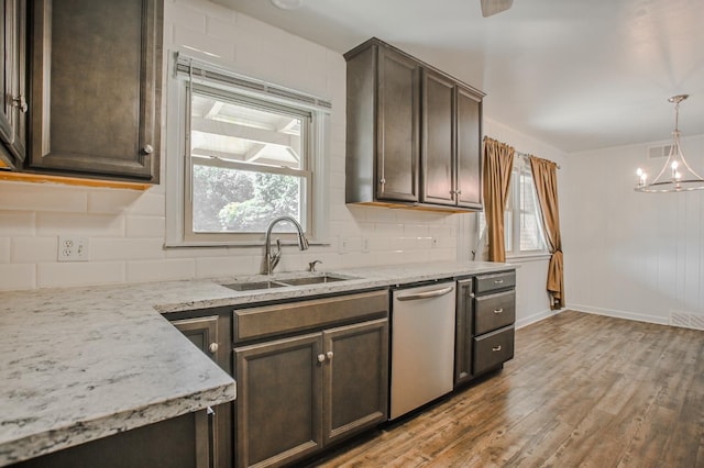 kitchen featuring stainless steel dishwasher, light stone countertops, sink, and dark brown cabinets