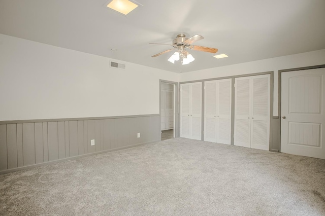 unfurnished bedroom with carpet floors, two closets, and ceiling fan