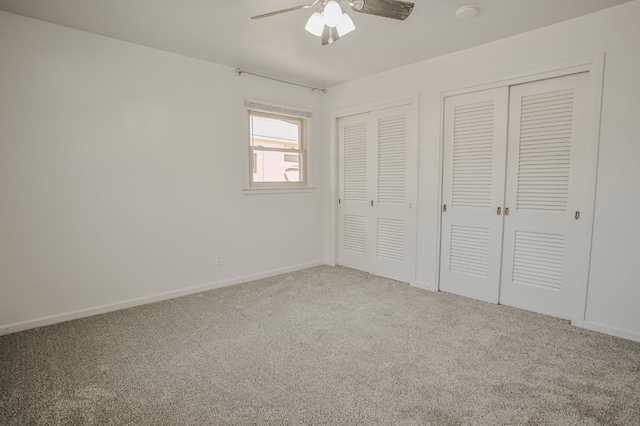 unfurnished bedroom featuring ceiling fan, multiple closets, and carpet flooring