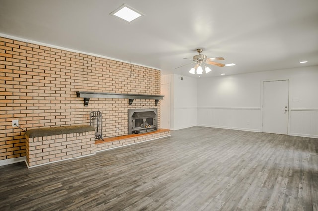 unfurnished living room featuring a fireplace, dark wood-type flooring, ceiling fan, and brick wall