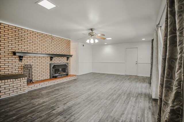 unfurnished living room with a brick fireplace, wood-type flooring, and ceiling fan