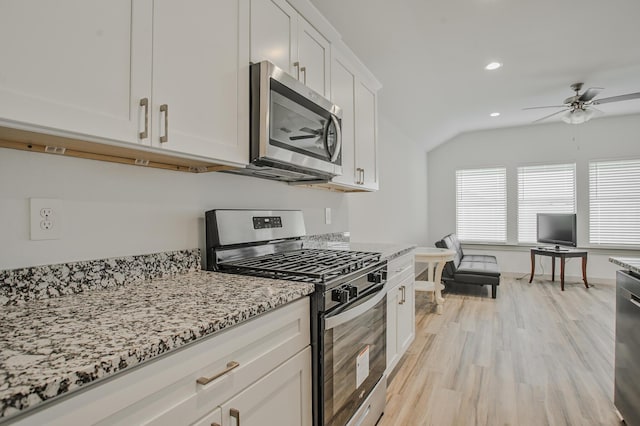 kitchen featuring light wood-style flooring, appliances with stainless steel finishes, ceiling fan, light stone countertops, and vaulted ceiling
