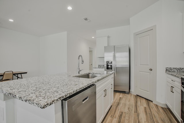 kitchen featuring a sink, white cabinets, stainless steel appliances, and light wood-type flooring