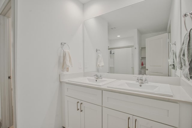 full bathroom with double vanity, a sink, and a shower stall