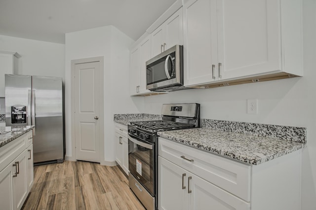 kitchen featuring light stone counters, white cabinets, appliances with stainless steel finishes, and light wood-type flooring