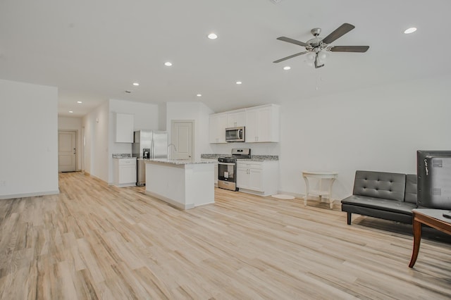 kitchen featuring light stone counters, white cabinets, stainless steel appliances, light wood-type flooring, and recessed lighting
