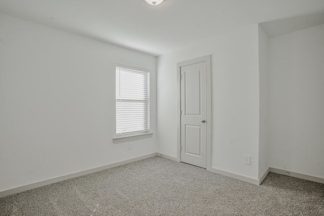unfurnished room with baseboards and light carpet