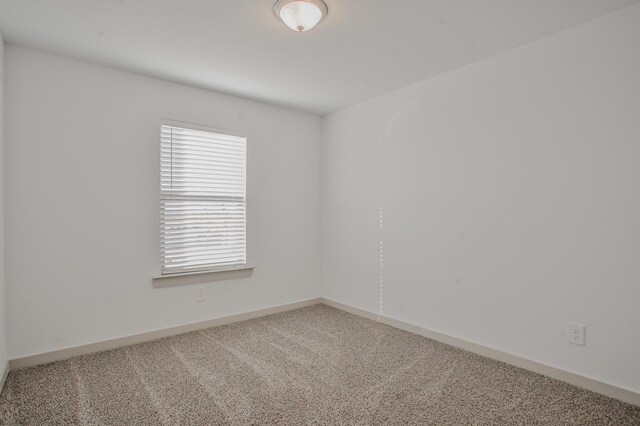 unfurnished room with carpet and baseboards