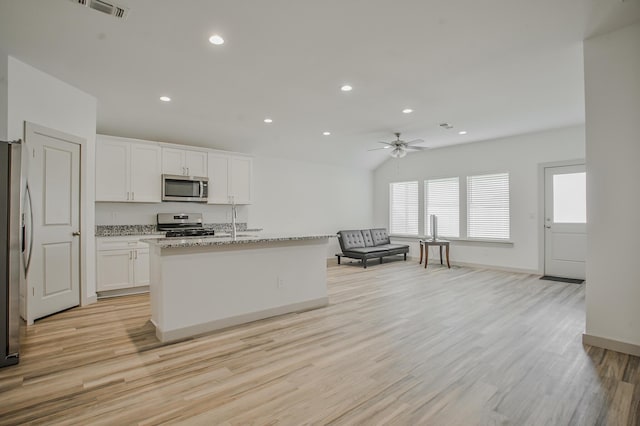 kitchen with light stone counters, stainless steel appliances, light wood-style floors, white cabinets, and ceiling fan