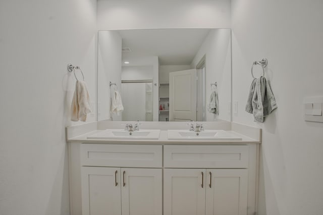 full bath featuring a shower with shower door, double vanity, and a sink