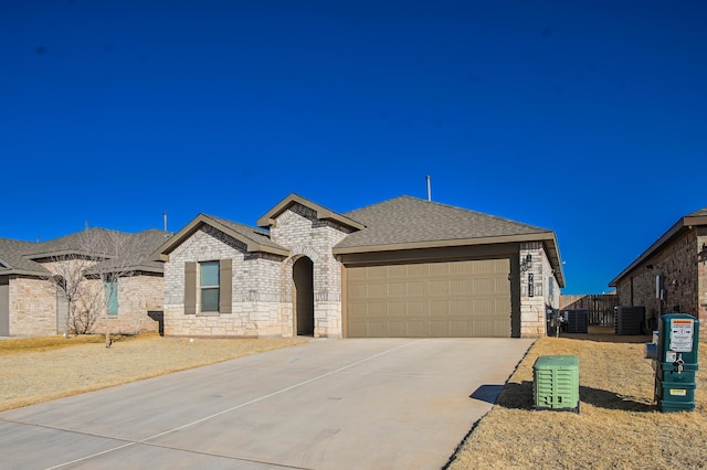 view of front of property featuring driveway, a shingled roof, an attached garage, and stone siding