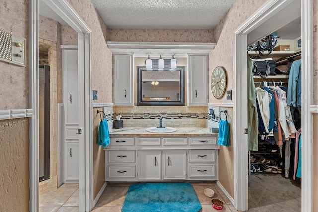4405 56th St, Lubbock, TX 79414 - full bath with vanity, a walk in closet, tile patterned floors, a textured ceiling, and backsplash