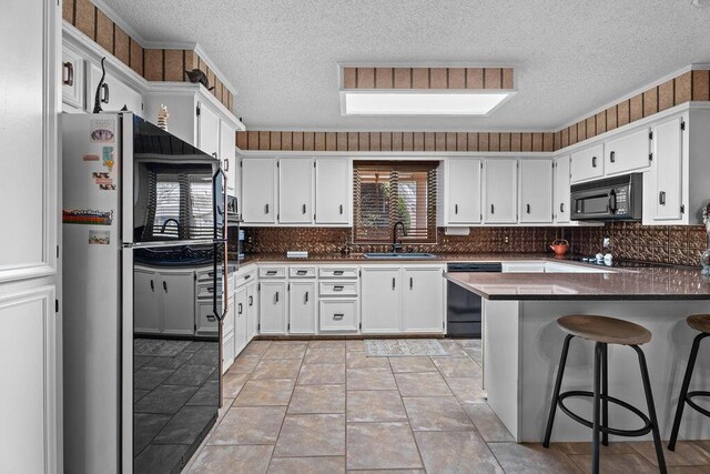 4405 56th St, Lubbock, TX 79414 - kitchen featuring black microwave, a sink, dishwasher, fridge, and a textured ceiling