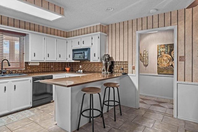 4405 56th St, Lubbock, TX 79414 - kitchen featuring black appliances, a sink, a textured ceiling, white cabinetry, and a peninsula