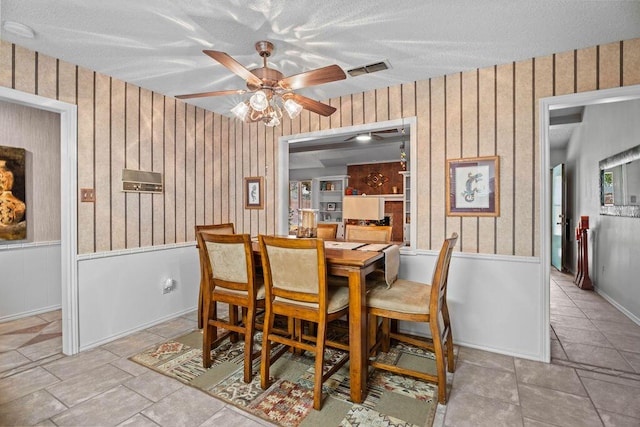 4405 56th St, Lubbock, TX 79414 - dining space featuring a ceiling fan, wood walls, and a textured ceiling