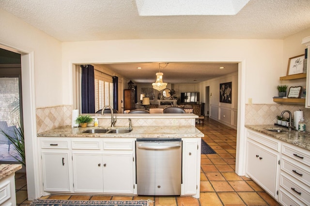 kitchen with stainless steel dishwasher, kitchen peninsula, sink, and white cabinets